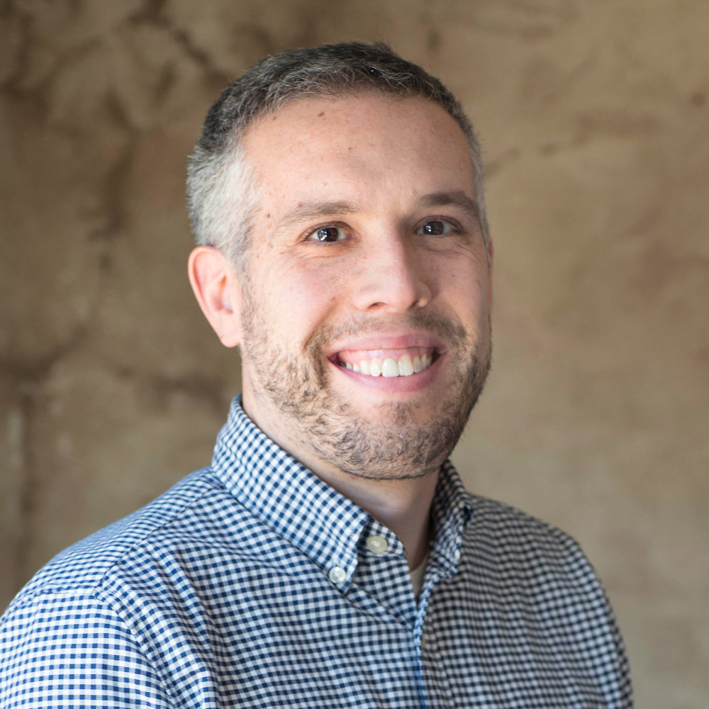 Headshot of David Rasch with a bland concrete background